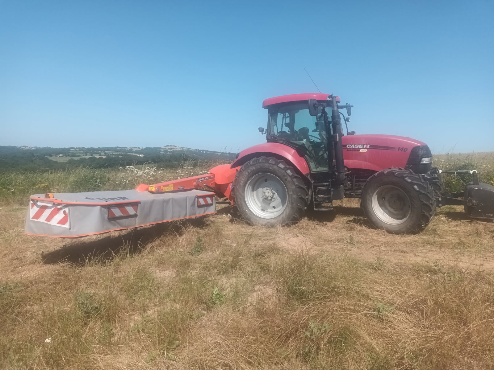 Tracteur Case IH 140 avec faucheuse en prairie estivale à Aveyron pour md-services-mecanique-hydraulique-aveyron