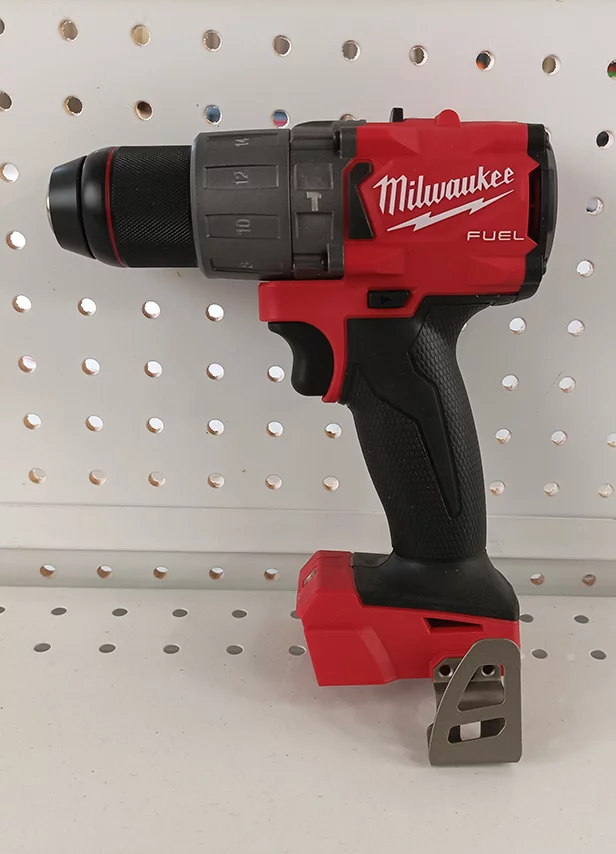 Perceuse-visseuse Milwaukee rouge sur panneau perforé chez md-services-mecanique-hydraulique-aveyron en Aveyron