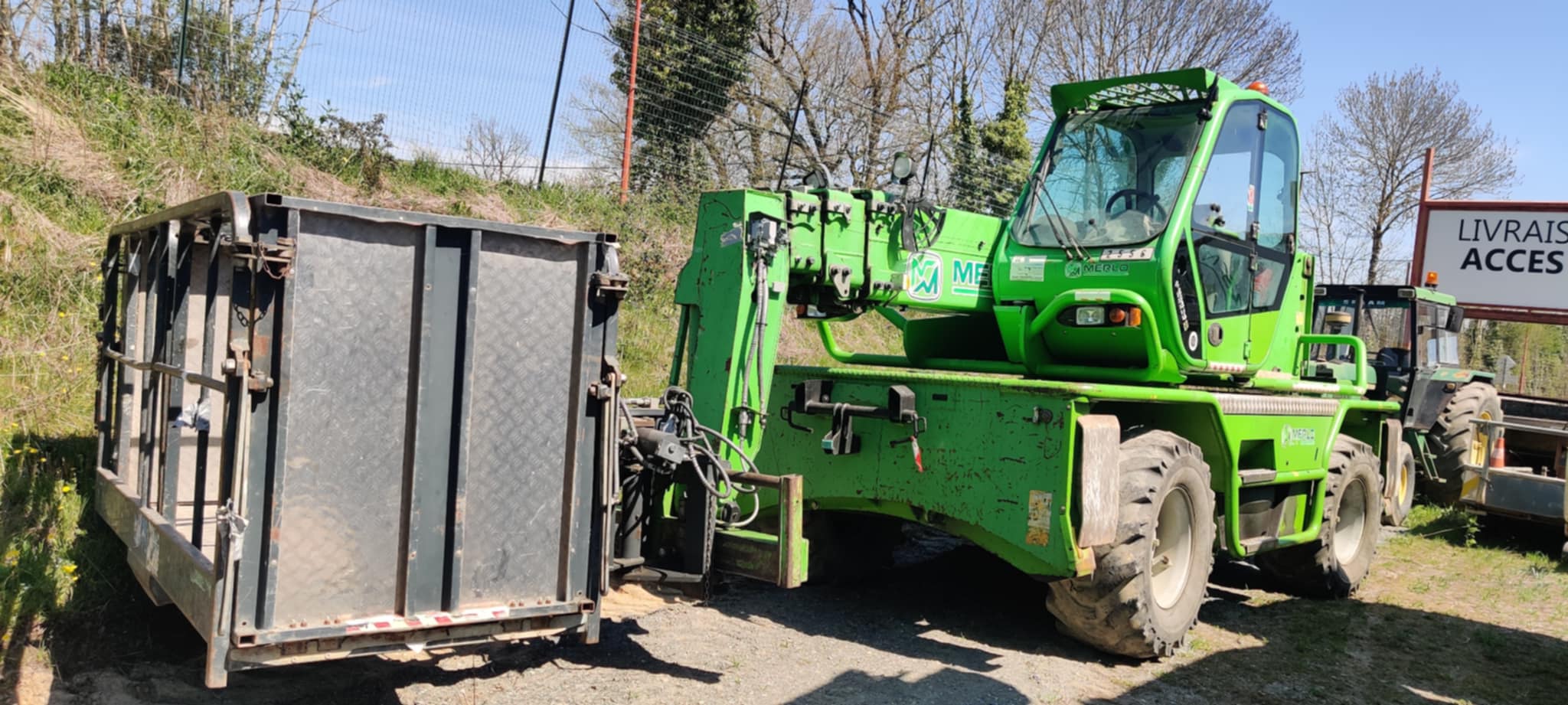 Chariot télescopique Merlo soulevant une benne sur chantier pour md-services-mecanique-hydraulique-aveyron en Aveyron